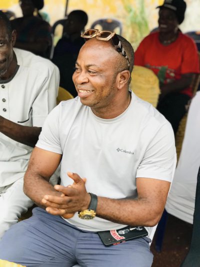 A smiling guest in a white t-shirt seated at the sports day.