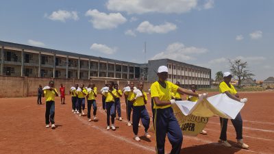 School band members in yellow shirts playing drums on the running track.