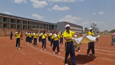 The yellow-shirted school band playing drums as they march around the track.