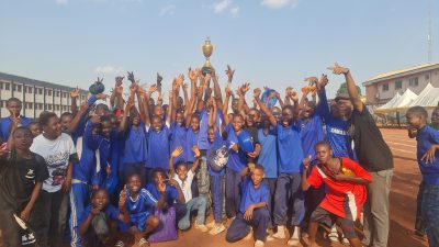 A house team in blue jerseys cheering with their arms raised as a trophy is held aloft.